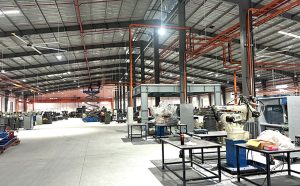 Không gian bên trong nhà máy công nghiệp hiện đại với cánh tay robot và hệ thống đường ống kỹ thuật