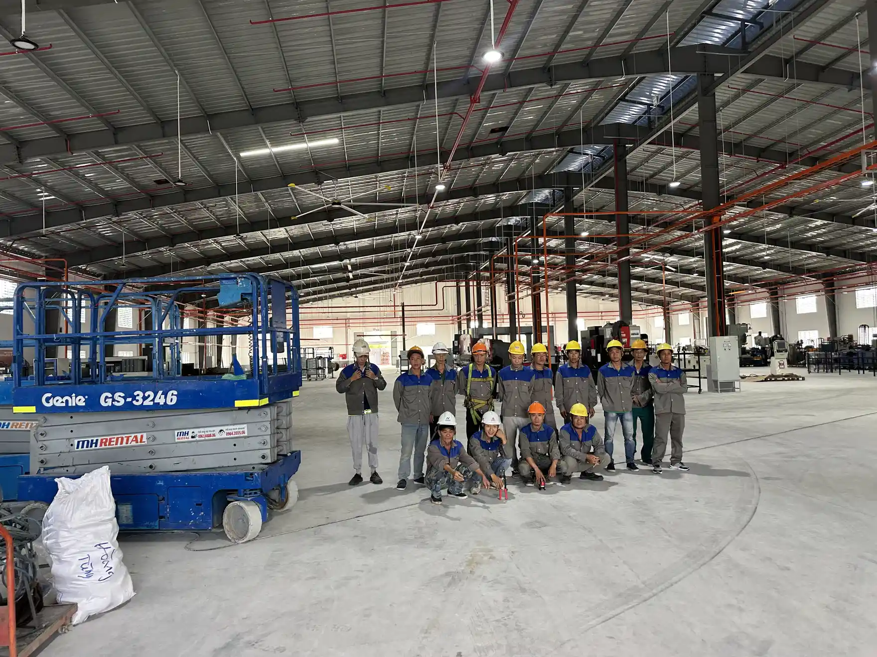 Đội thi công điện làm việc trên xe nâng người trong nhà xưởng
