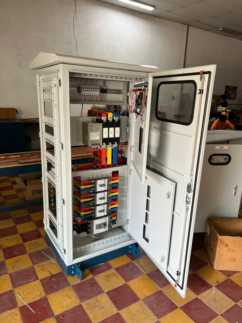 Tủ điện phân phối mở cửa, bên trong có thanh cái đồng sơn màu pha và các aptomat khối